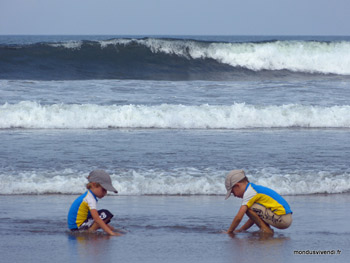 ENFANTS JOUANT DEVANT LES VAGUES